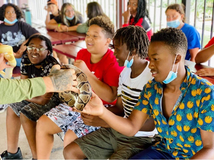 A group of children attending an educational show; they are being shown snakes.
